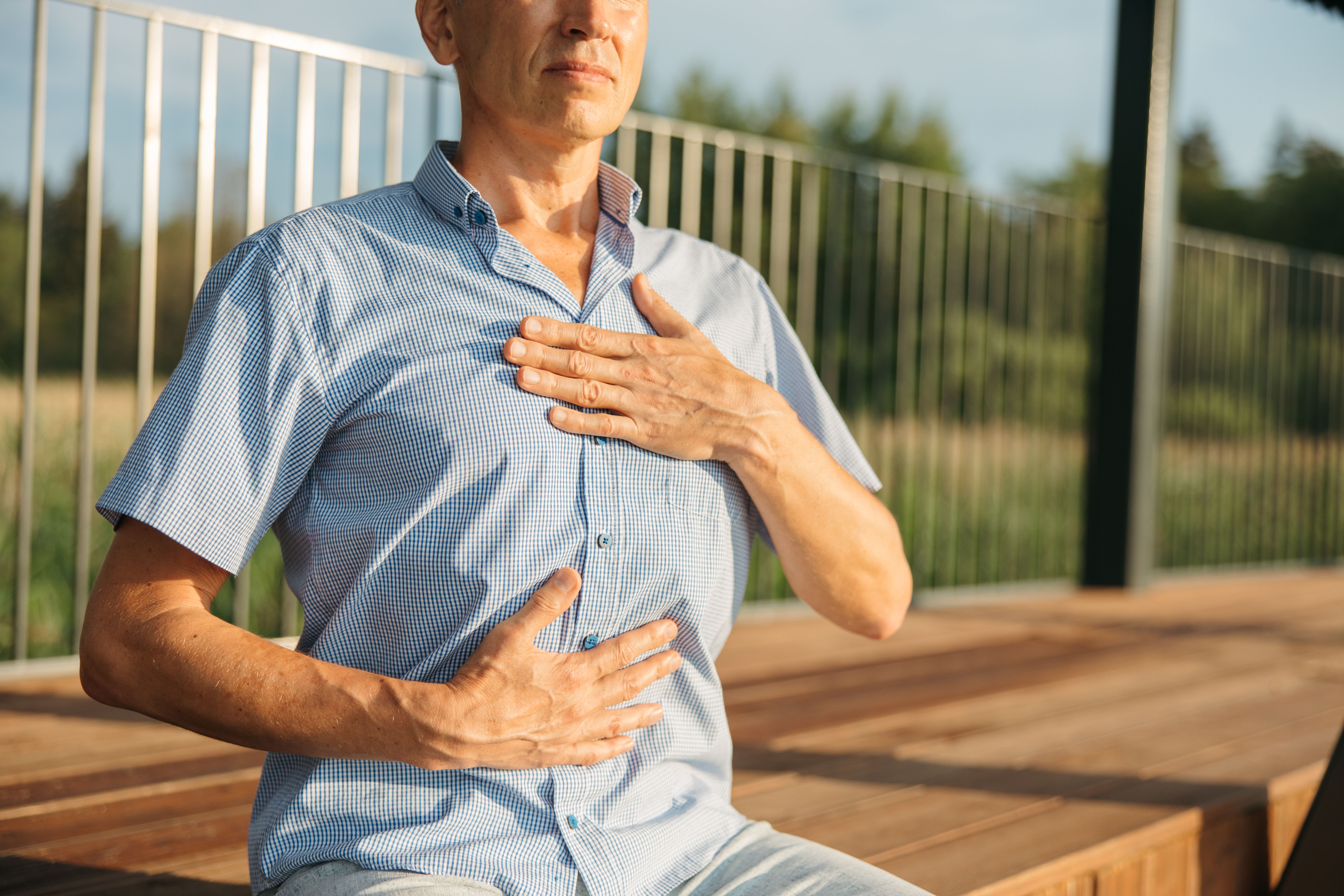 Man practicing relaxed breathing with hands on his chest and abdomen outdoors, illustrating a coping strategy for nicotine urges.