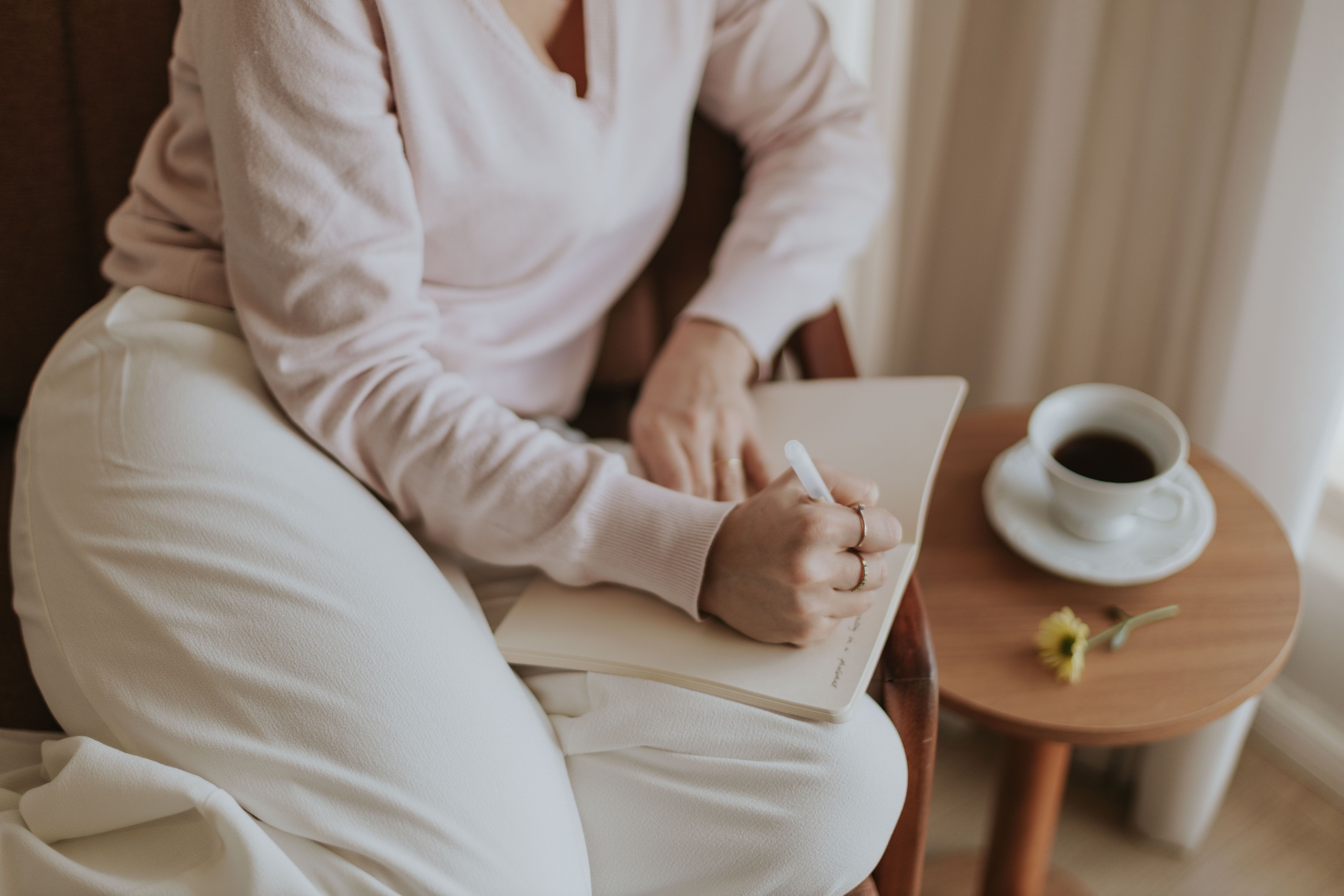 Person journaling at a table with a warm drink, illustrating urge tracking and reflection during nicotine recovery.